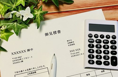 御見積書と白い電卓と白いペン（木目）